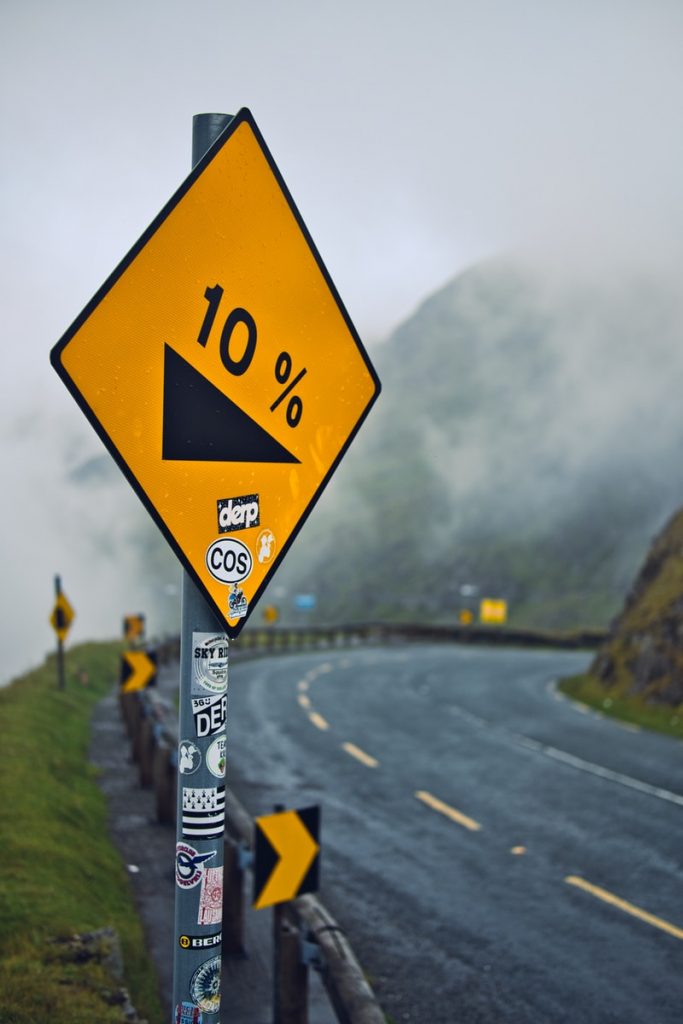 A road sign on a mountain road indicating a downward grade